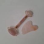 Rodillo facial y piedra gua sha de cuarzo rosa sobre fondo gris